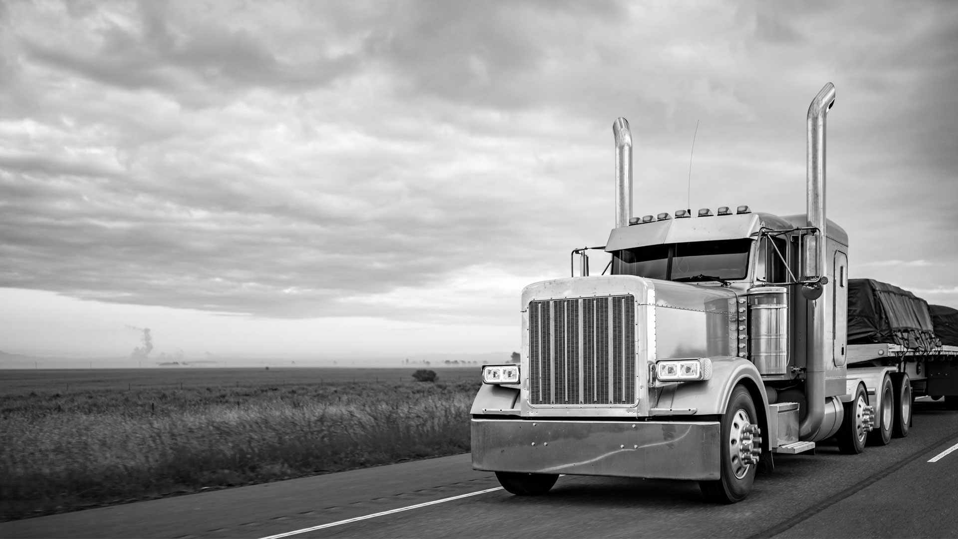 A freight truck traveling on an open highway at dusk